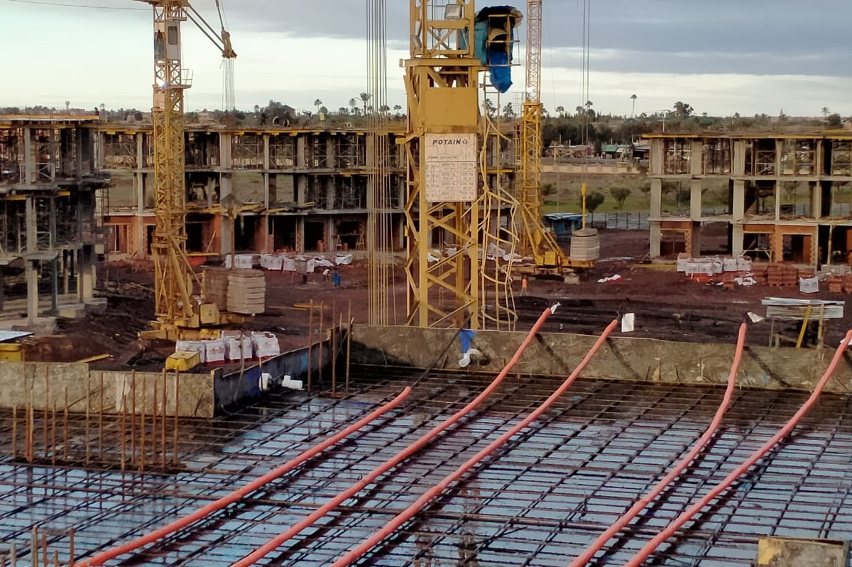 Unbonded monostrand tendon in red sheath with anchorage zone and conventional slab reinforcement in a post-tensioned concrete slab